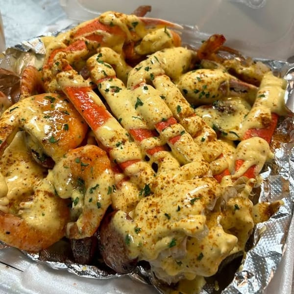 Soul food seafood boil with crab legs, shrimp, and potatoes covered in creamy sauce and seasoning.